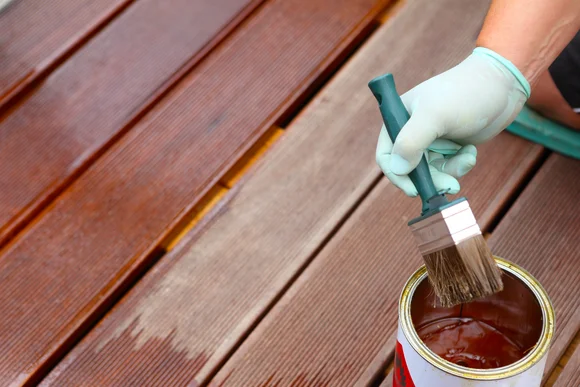 Terrassendielen werden mit Holzschutz bestrichen